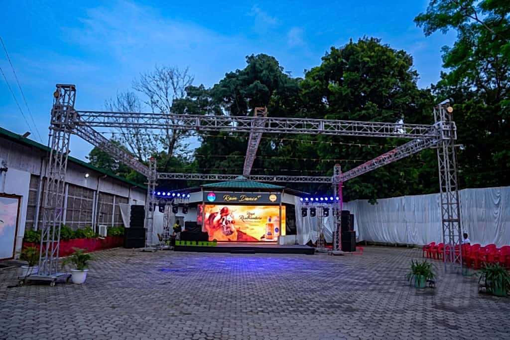 Outdoor rain-dance courtyard framed by aluminium box truss and LED stage at dusk