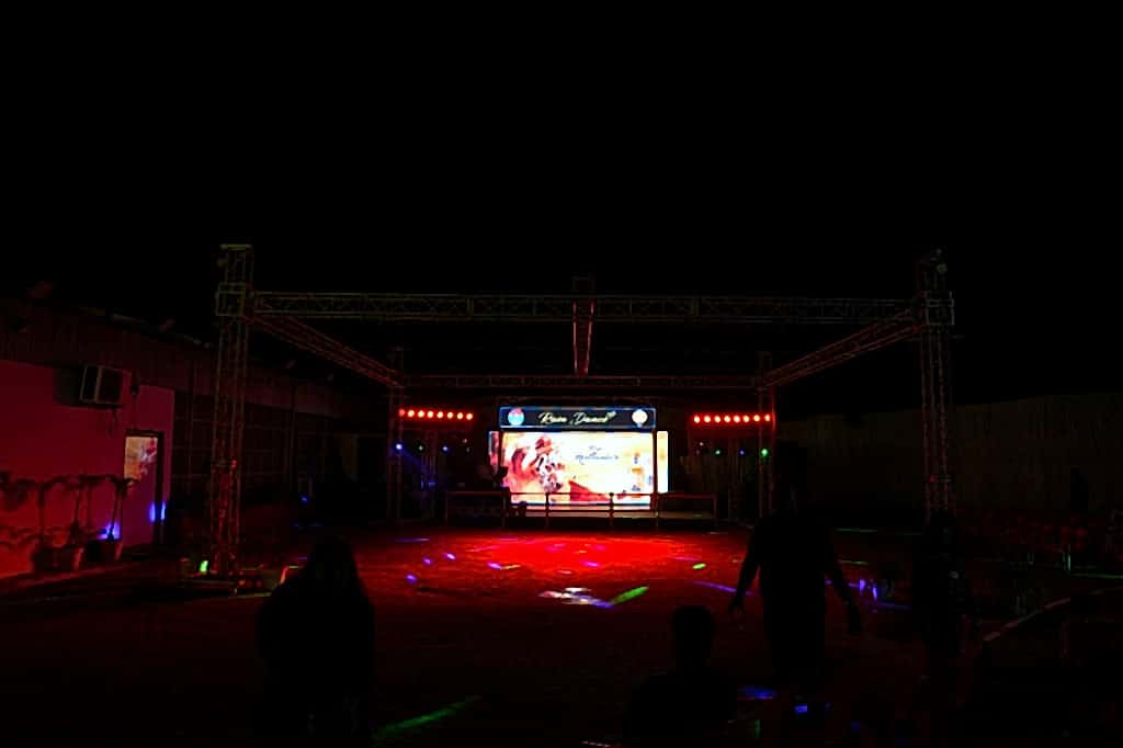 Night rain-dance stage with LED wall, colourful floor washes, and guest silhouettes