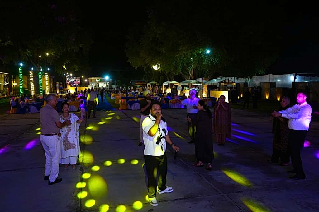 Live singer performing while couples dance on a lit outdoor paved floor