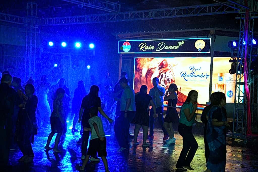Crowd dancing under Rain Dance Nite signage and LED backdrop with water spray