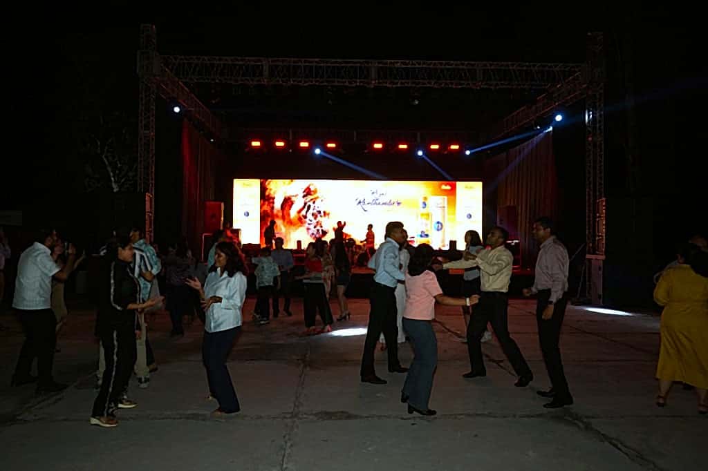 Guests dancing toward a brightly lit LED stage during an evening celebration