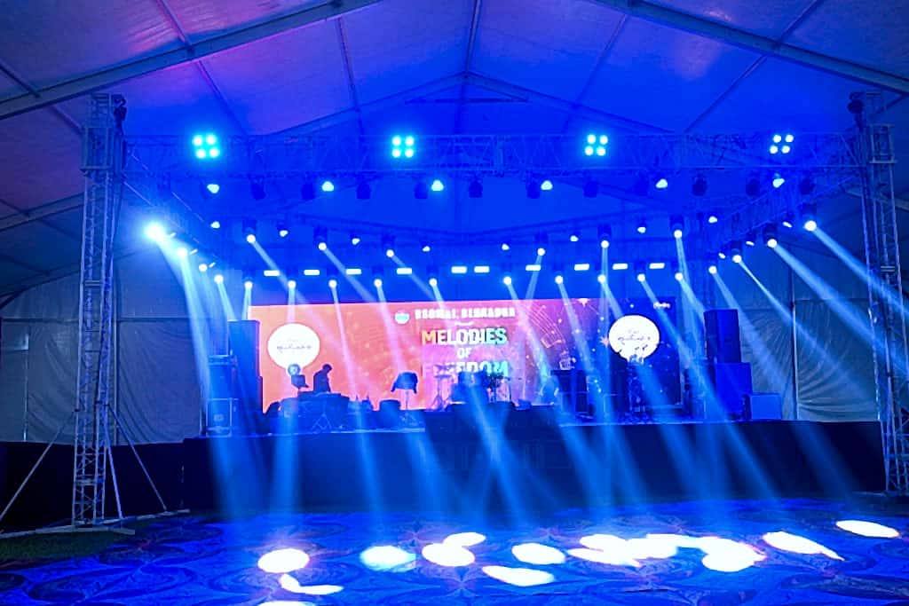 Indoor marquee stage for Melodies of Freedom with LED wall, truss lighting, and instruments