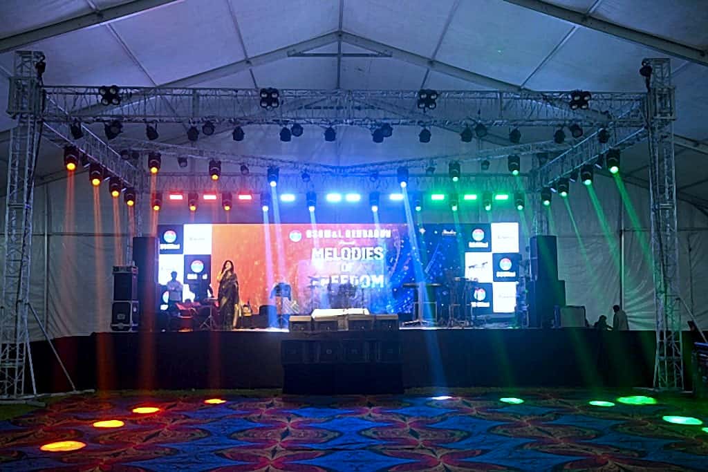 Melodies of Freedom stage under coloured beams with performer and band setup