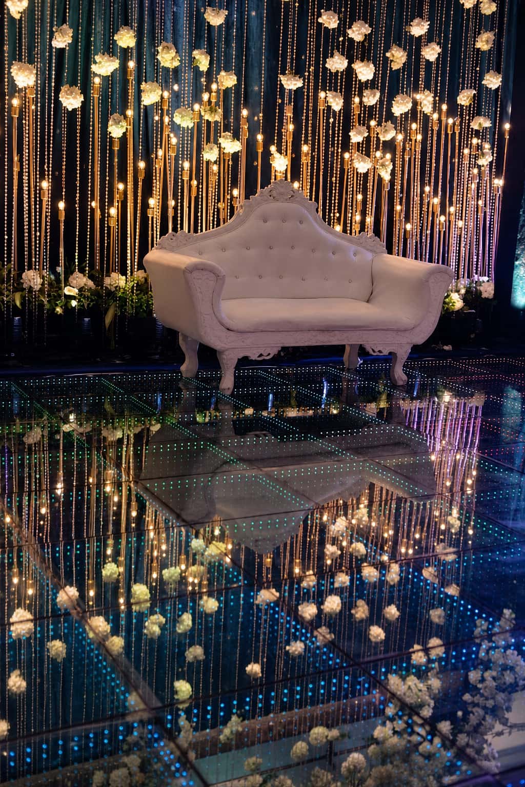 White velvet lounge on a mirrored LED floor with crystal light curtain